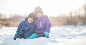 2 children sitting in a pile of snow