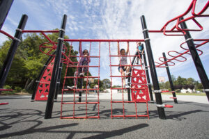 two kids climbing on playground equipment