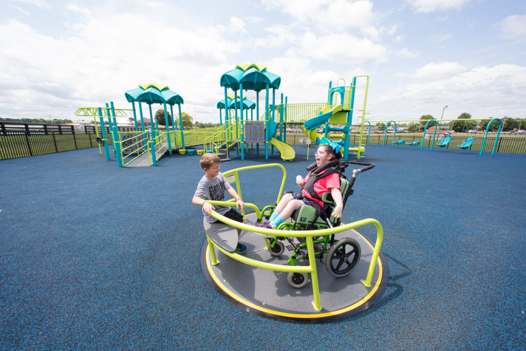 inclusive in-ground spinner with a young girl in a wheelchair using it