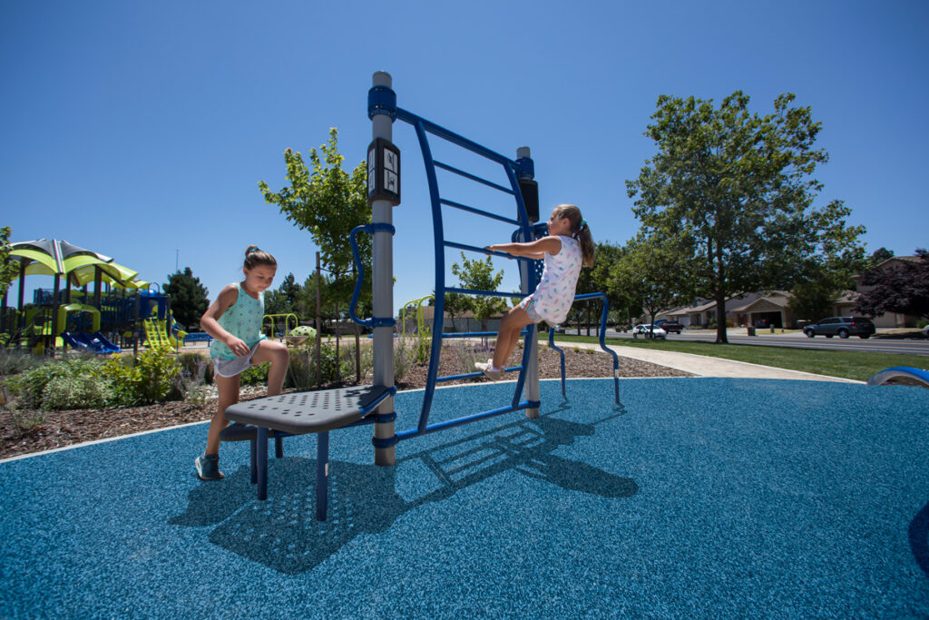 two young girls using platform and ladder elements on outdoor fitness equipment