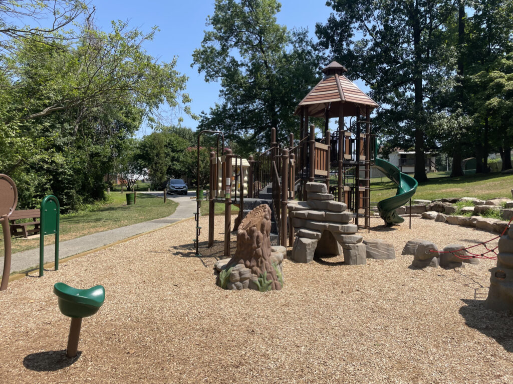 woodland themed playground with plastic rock and tree structures