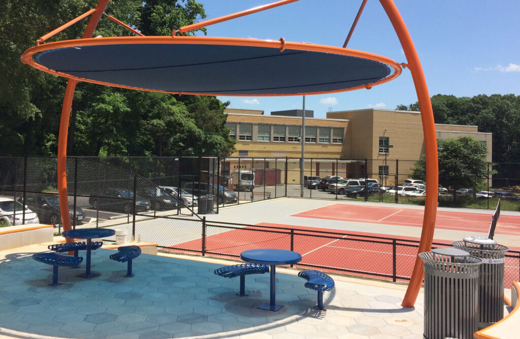 large orange shade structure installed by tennis courts