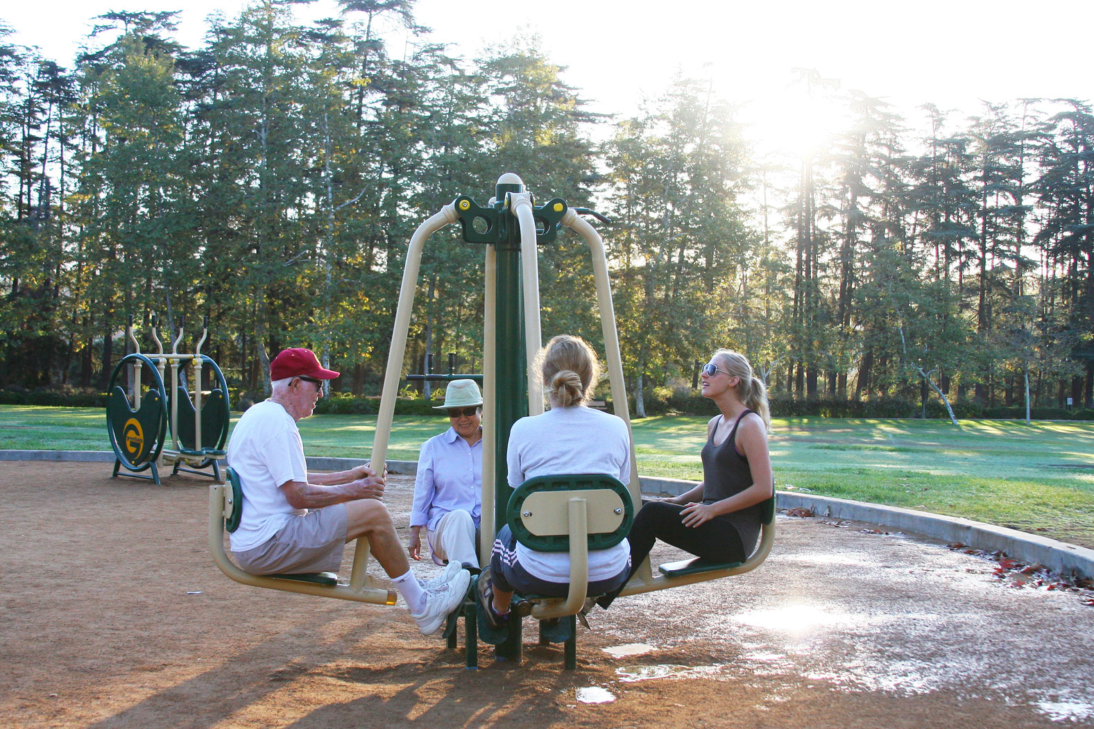 Adults using outdoor fitness equipment