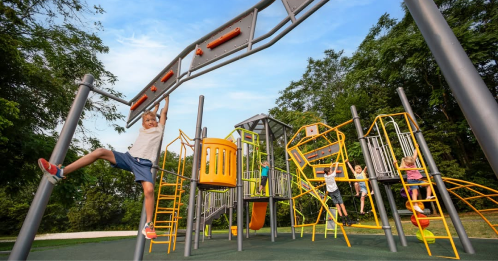 A kid swinging on the monkey bars at a playground designed by Metro Recreation.
