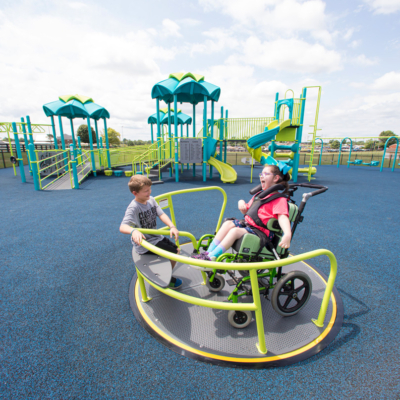 inclusive in-ground spinner with a young girl in a wheelchair using it