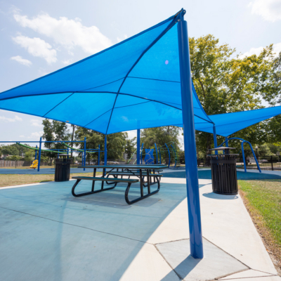 large blue shade structure covering picnic tables