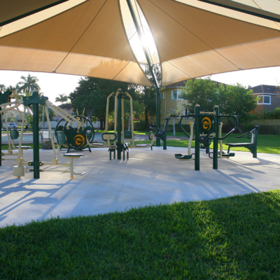 Greenfield outdoor fitness equipment under a large shade structure