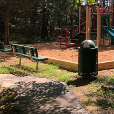 two green playground benches facing a playground
