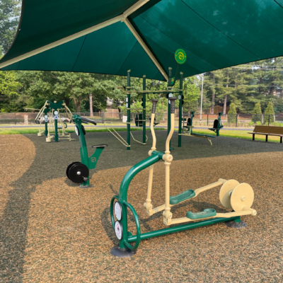 outdoor fitness equipment installed under a large green shade structure